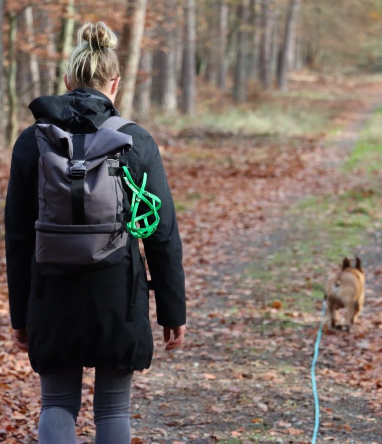 Hundetrainerin läuft mit Hund an Schleppleine im Wald